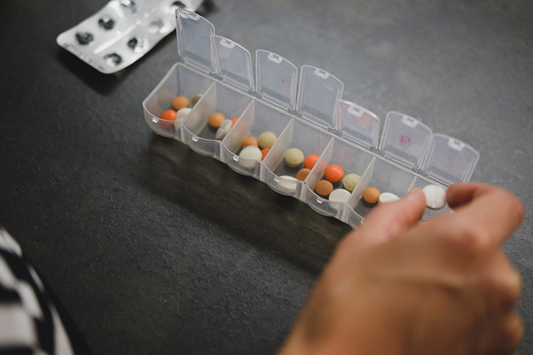 Hand puts coloured tablets into separate compartments
